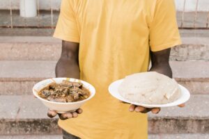 Person holding a plate of Tanzania local foods – Ugali served with meat and traditional vegetables