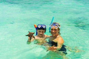 Best time for diving and snorkeling in Zanzibar showing mother and son discovering starfish while swimming in clear tropical waters
