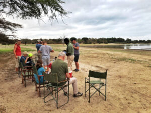 Family safari in Tanzania at Selous Game Reserve enjoying breakfast near a lake with safari Land Rover during morning wildlife experience