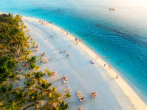 Best time for beach holidays in Zanzibar showcasing aerial view of Kendwa beach with palm trees, white sand, and turquoise Indian Ocean at sunset