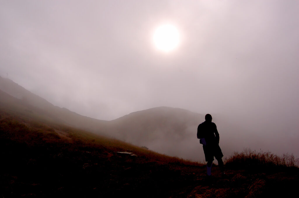 Fullmoon hiking in Tanzania – male hiker standing on a mountain summit under a bright full moon