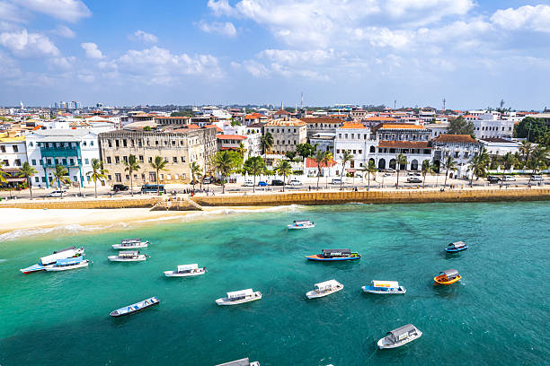 Best time to visit Zanzibar featuring Stone Town boats anchored in turquoise Indian Ocean waters during sunny beach holiday season